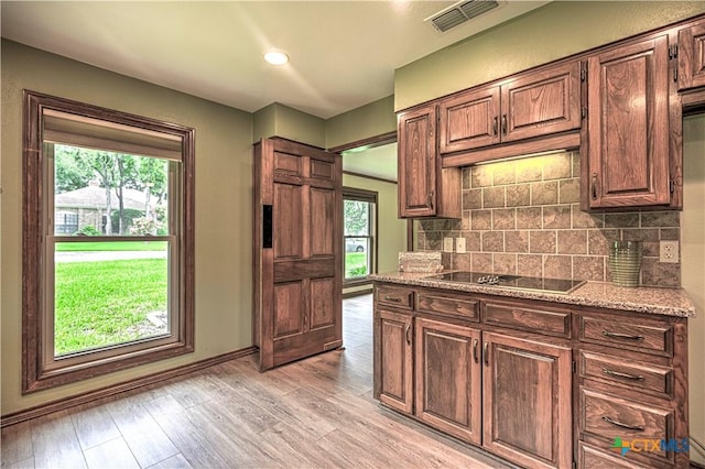 2702 Olympia Dr, Temple, TX 76502 - kitchen featuring black electric cooktop, backsplash, light wood-style flooring, light stone countertops, and recessed lighting