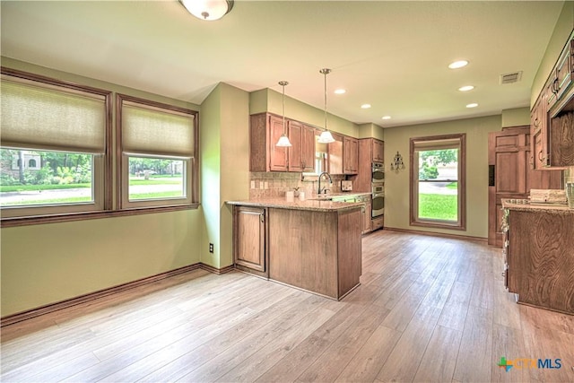 2702 Olympia Dr, Temple, TX 76502 - kitchen with a peninsula, brown cabinetry, light stone countertops, tasteful backsplash, and recessed lighting
