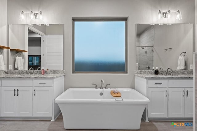 2716 Prairie Chapel Ct, Temple, TX 76502 - full bath featuring a shower stall, a freestanding bath, two vanities, and wood finished floors