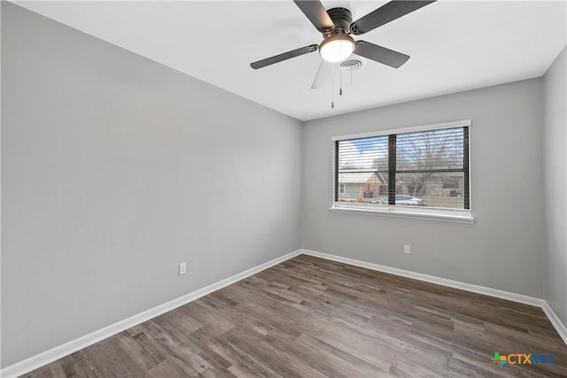 empty room with a ceiling fan, visible vents, baseboards, and dark wood-type flooring