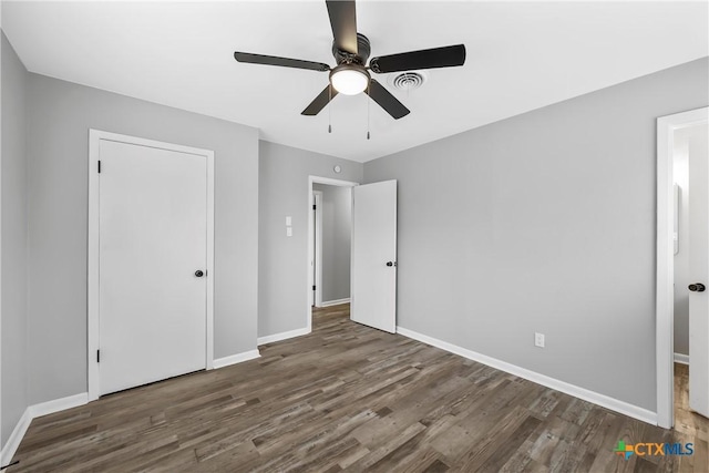 unfurnished bedroom featuring a ceiling fan, baseboards, and dark wood-type flooring