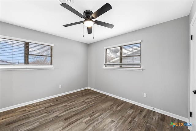 empty room with dark wood-style flooring, a ceiling fan, and baseboards