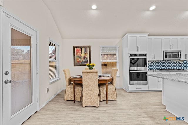 kitchen featuring light stone countertops, white cabinetry, appliances with stainless steel finishes, and light hardwood / wood-style floors