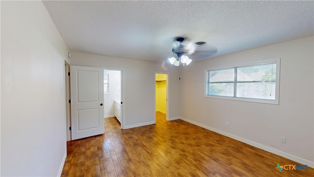 107 Hampton Ct, Victoria, TX 77904 - unfurnished bedroom with light wood-style floors, a textured ceiling, a spacious closet, a closet, and a ceiling fan