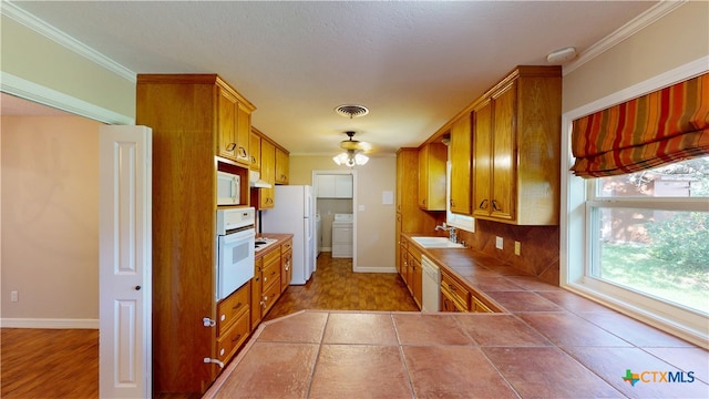 107 Hampton Ct, Victoria, TX 77904 - kitchen with washer / dryer, white appliances, tile counters, crown molding, and brown cabinets