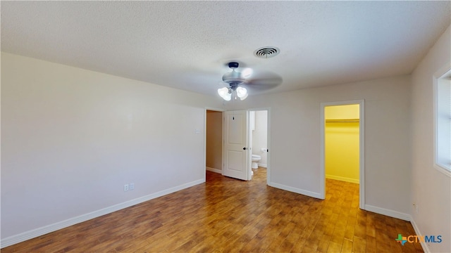 107 Hampton Ct, Victoria, TX 77904 - unfurnished bedroom featuring a spacious closet, wood finished floors, a closet, a textured ceiling, and a ceiling fan