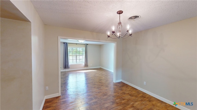 107 Hampton Ct, Victoria, TX 77904 - empty room with wood finished floors, a textured ceiling, and a chandelier