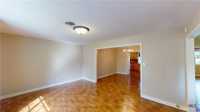 107 Hampton Ct, Victoria, TX 77904 - empty room featuring a chandelier, wood finished floors, and a textured ceiling