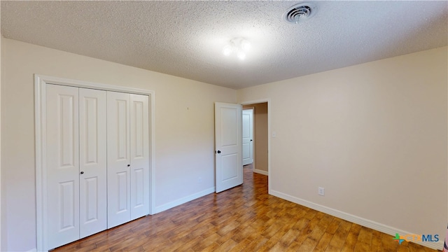 107 Hampton Ct, Victoria, TX 77904 - unfurnished bedroom featuring light wood-style flooring, a closet, and a textured ceiling