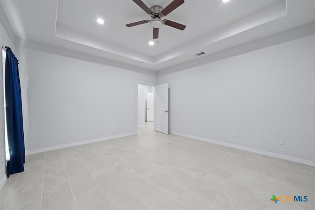 empty room featuring a tray ceiling and ceiling fan