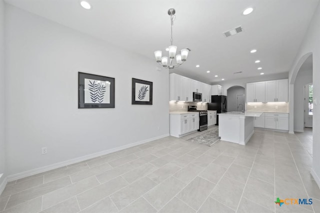 kitchen with decorative light fixtures, white cabinetry, an island with sink, and appliances with stainless steel finishes