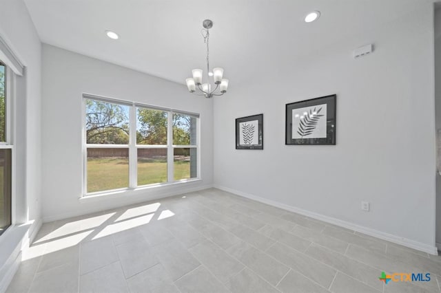 empty room featuring a wealth of natural light, light tile patterned floors, and an inviting chandelier