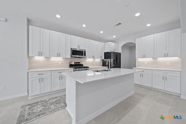 kitchen featuring white cabinets, sink, stainless steel appliances, and a kitchen island with sink