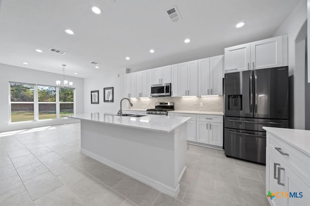 kitchen with a kitchen island with sink, hanging light fixtures, appliances with stainless steel finishes, a notable chandelier, and white cabinetry