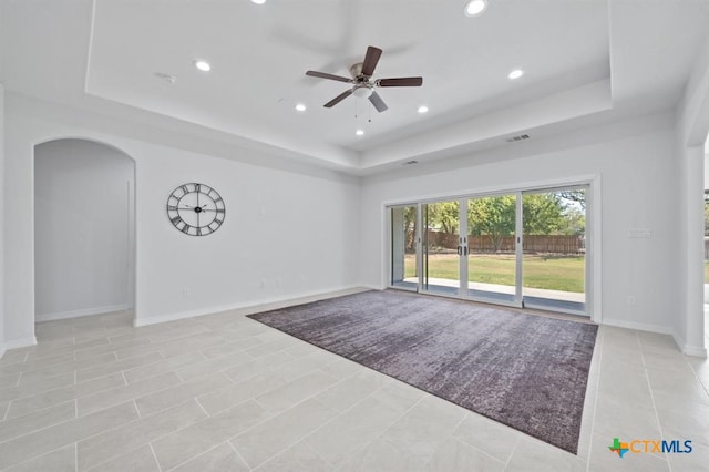 tiled spare room featuring a raised ceiling and ceiling fan