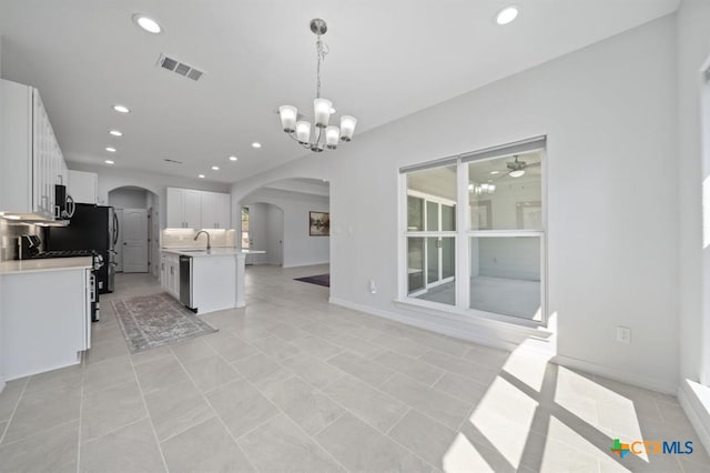 kitchen with sink, decorative light fixtures, a center island with sink, white cabinets, and ceiling fan with notable chandelier