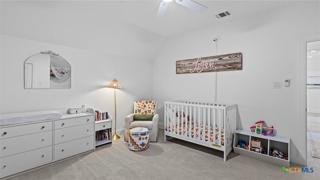 carpeted bedroom with ceiling fan, a crib, and vaulted ceiling