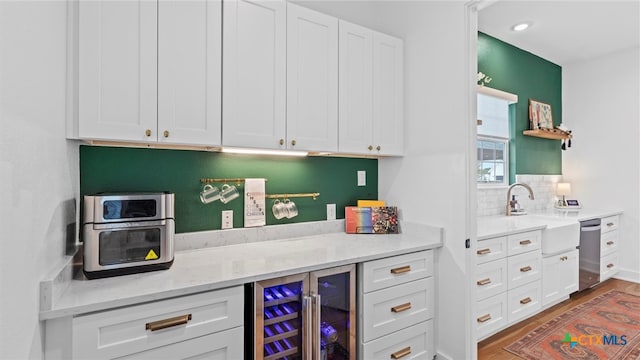 kitchen featuring wine cooler, sink, white cabinets, and wood-type flooring