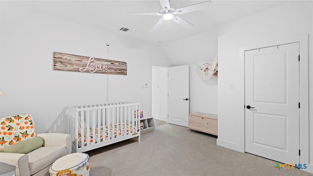 carpeted bedroom featuring vaulted ceiling, ceiling fan, and a crib