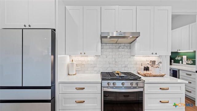 kitchen featuring gas range, light stone counters, white cabinetry, and fridge