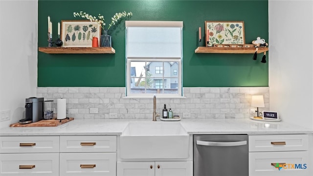 kitchen featuring light stone countertops, white cabinetry, stainless steel dishwasher, and sink