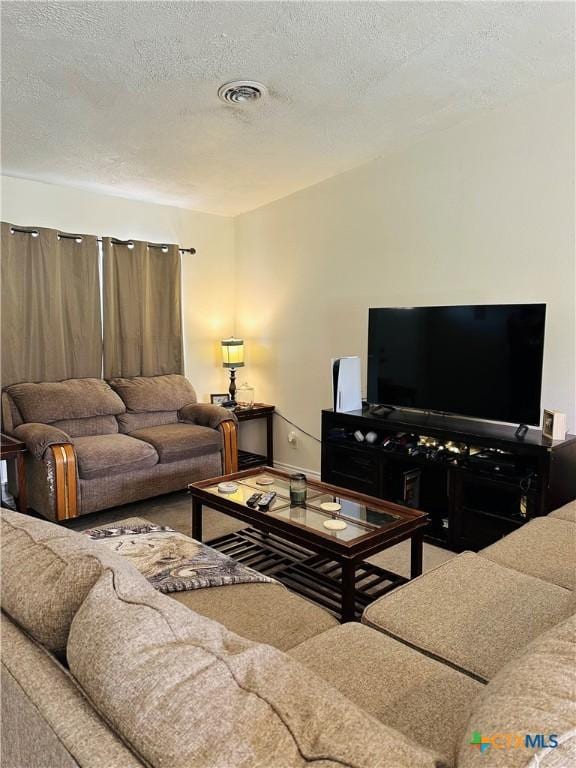 living room featuring visible vents, baseboards, and a textured ceiling
