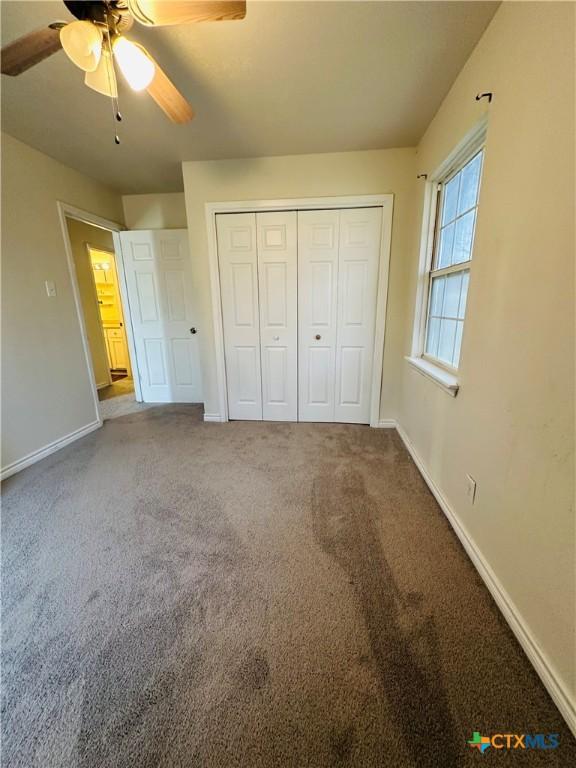 unfurnished bedroom featuring a closet, carpet flooring, a ceiling fan, and baseboards