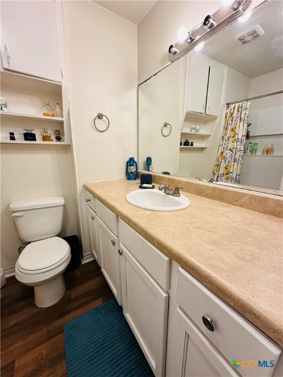 full bathroom featuring vanity, a shower with curtain, wood finished floors, visible vents, and toilet