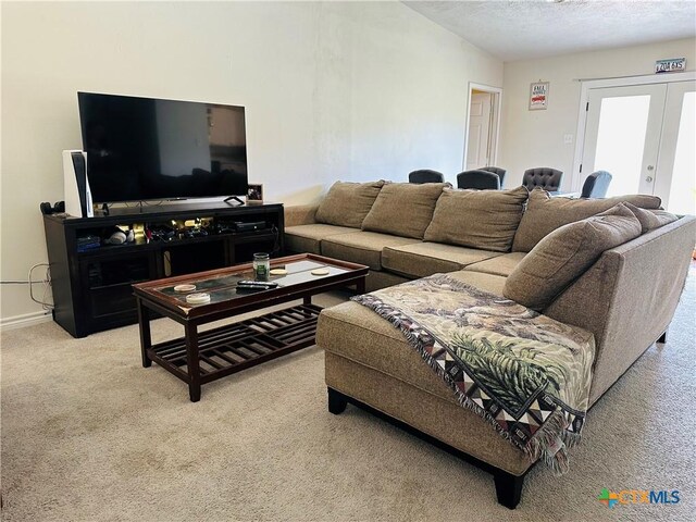 carpeted living room with french doors, baseboards, and a textured ceiling