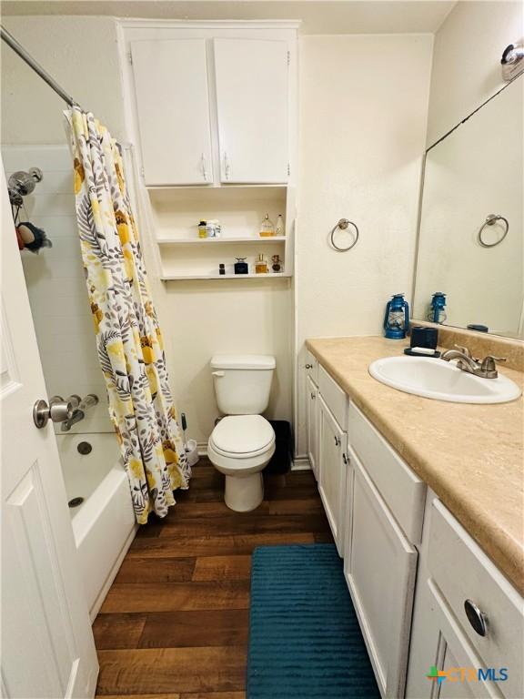 bathroom with vanity, toilet, wood finished floors, and shower / tub combo with curtain