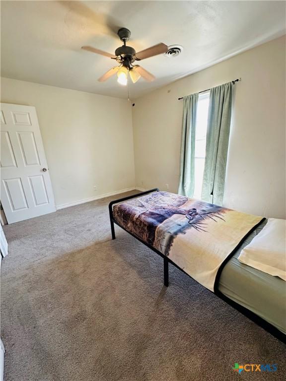 carpeted bedroom with a ceiling fan, baseboards, and visible vents