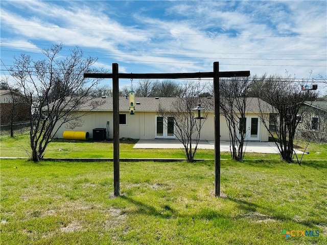 rear view of property featuring fence, central AC unit, french doors, a yard, and a patio area