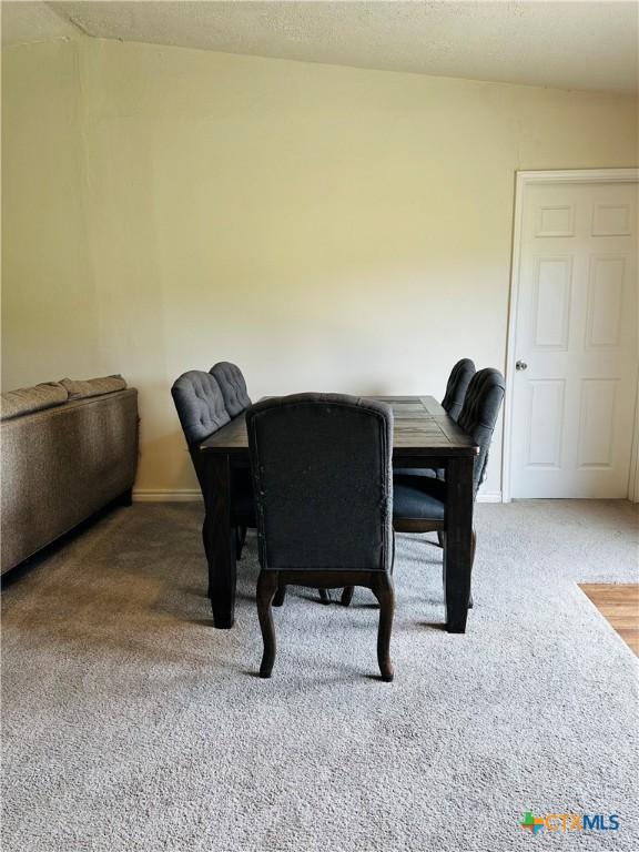 carpeted dining space featuring baseboards and a textured ceiling