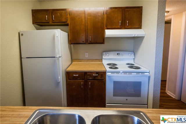 kitchen featuring sink, white appliances, a textured ceiling, and dark hardwood / wood-style floors