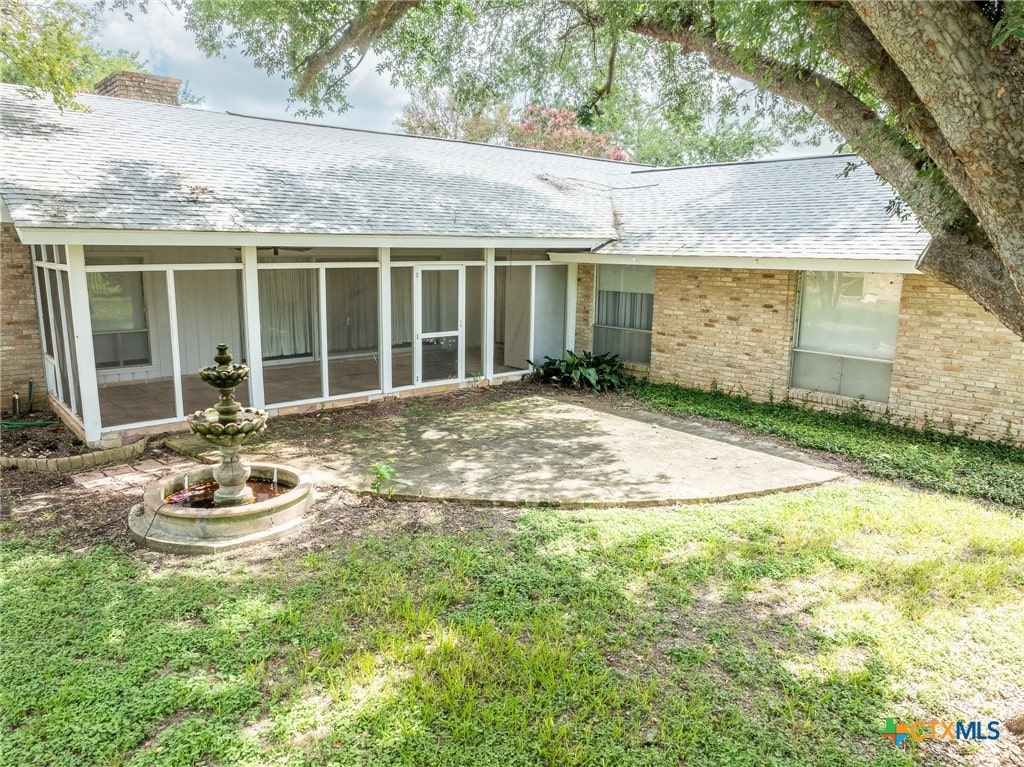 rear view of property with a sunroom and a lawn