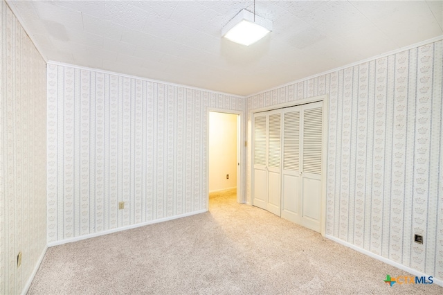 unfurnished bedroom featuring light colored carpet, crown molding, and a closet