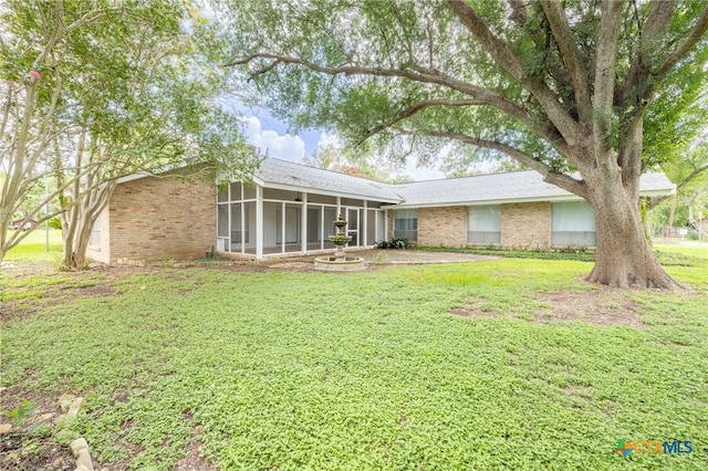 exterior space featuring a sunroom, a patio area, and a lawn