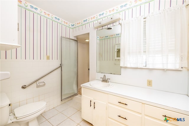 bathroom with vanity, a shower with door, tile patterned flooring, toilet, and tile walls