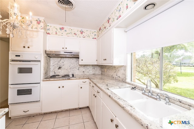 kitchen featuring backsplash, white appliances, sink, light tile patterned floors, and white cabinetry