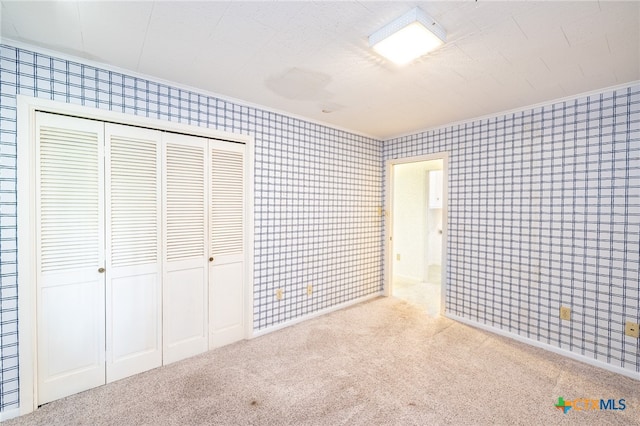 unfurnished bedroom with light colored carpet and a closet