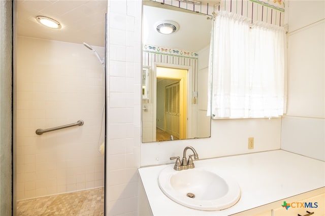 bathroom with a tile shower and vanity