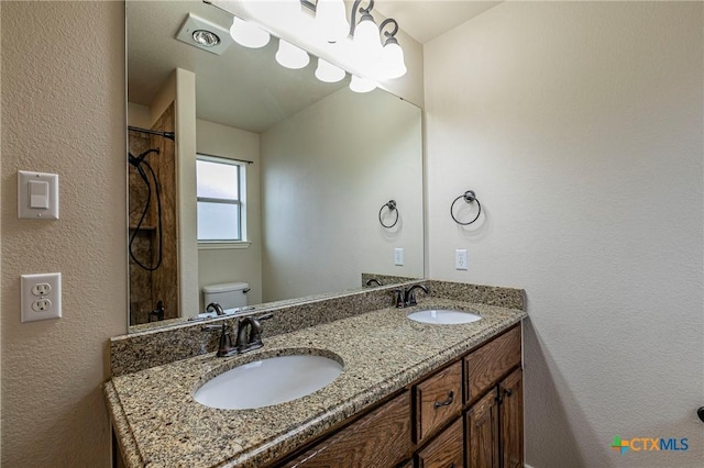 full bath with toilet, a sink, and double vanity