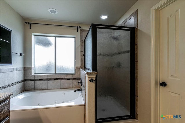 bathroom with a tub with jets, a stall shower, and recessed lighting