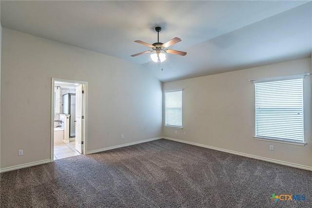 carpeted spare room featuring baseboards, ceiling fan, and vaulted ceiling