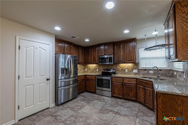 kitchen with stainless steel appliances, decorative backsplash, a sink, light stone counters, and visible vents