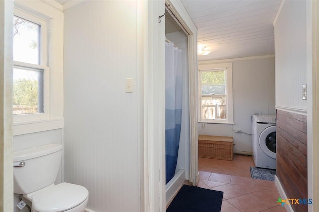 bathroom featuring tile patterned floors, toilet, washer / dryer, and a wealth of natural light