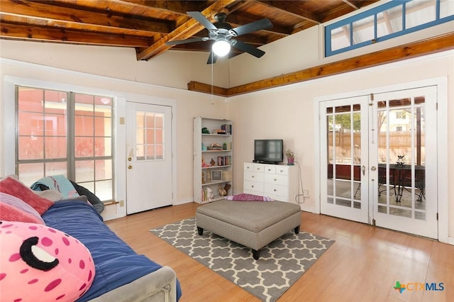 living room featuring ceiling fan, french doors, vaulted ceiling with beams, wood ceiling, and light wood-type flooring