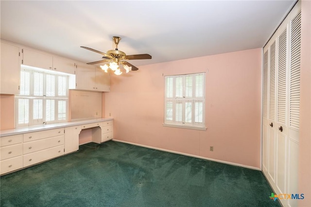 unfurnished bedroom featuring baseboards, built in desk, dark carpet, and a closet