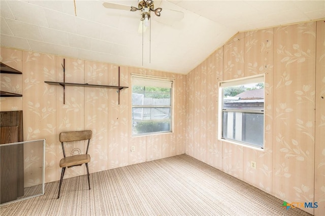 unfurnished room with a healthy amount of sunlight, ceiling fan, carpet flooring, and lofted ceiling