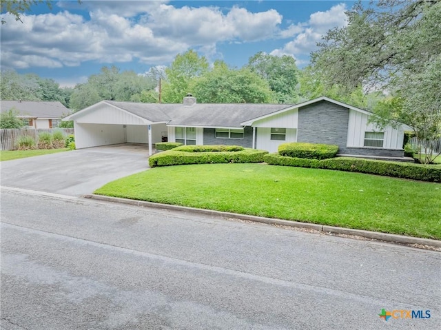 ranch-style house featuring board and batten siding, a front yard, a chimney, a carport, and driveway